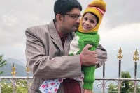 A father holds his young daughter outside.