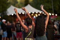 Two people dancing with their arms in the air at an outdoor concert.