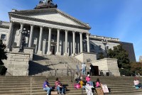 A small group of people sit and stand on the steps of the South Carolina State House.